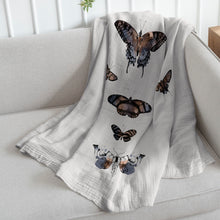 Load image into Gallery viewer, white organic cotton baby quilt with butterfly print draped on a sofa