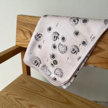 Load image into Gallery viewer, folded jersey baby blanket in gender neutral shell print hanging over back of a chair
