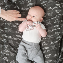 Load image into Gallery viewer, baby boy lying on our black and white printed muslin swaddle blanket
